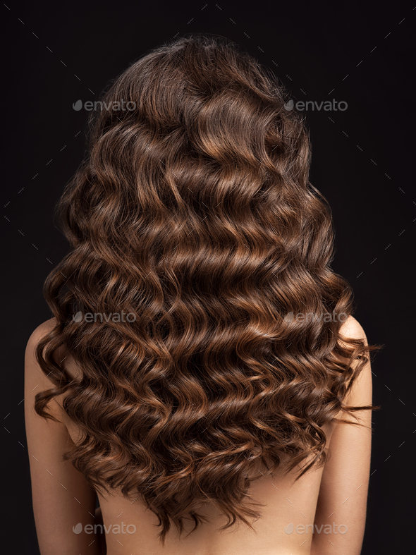 Girl with long, curly hair, rear view. Hair texture, close-up. Stock